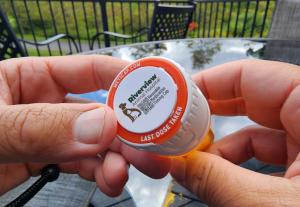 Meticap, a reusable medication timing cap, fits on existing 1-Clic pill vial lids. This Meticap has a veterinary practice logo on the top along with a QR code.