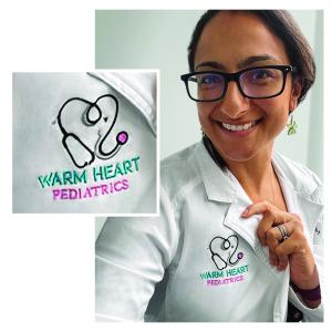 A photo of Dr. Krupa Playforth smiling and proudly wearing her lab coat with the embroidered logo on her lab coat