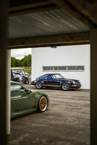 A classic Porsche 911 in black and a modern Porsche 911 Carrera GTS in classic green. Both cars are available under financing through Woodside Credit.