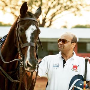 man stands next to polo horse