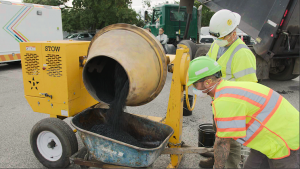 Workers from Modern Hydrogen and National Grid paving teams prepare a batch of carbon-sequestering asphalt during a demonstration in Long Island. The mixture, made with Modern Carbon, solid carbon derived from methane pyrolysis, is poured from a concrete 