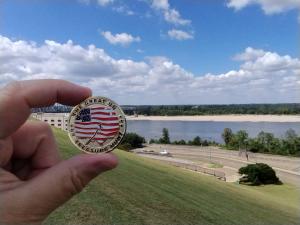 A Great US Treasure Hunt coin is shown in front of the Mississippi River. Five coins will be hidden both east and west of the mighty river.