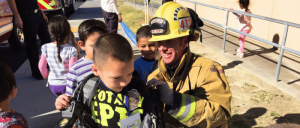 A firefighter interacting with children during a school visit.