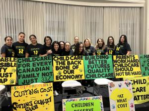 People in matching T-shirts behind homemade signs in large room