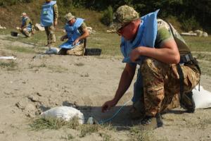 Ukrainian deminers engaged in hands on practice during training on a range used by humanitarian demining course instructors in Kosovo