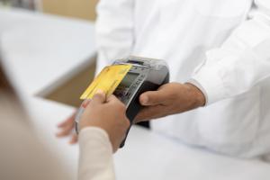 Customer making payment using credit card contactless with a credit card reader machine in modern pharmacy