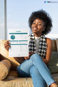 A smiling person sits on a couch, holding up a printed total rewards statement created using the TRS Express software. The statement provides a detailed breakdown of various compensation and benefits components, featuring a pie chart that summarizes their total rewards.