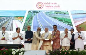 Savji and Ghanshyam Dholakia give a peacock to PM Modi on stage during Bharatmata Sarovar's inauguration.