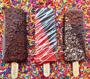 This image is of three of our custom dipped and topped gelato and sorbetto bars in front of a background of sprinkles.