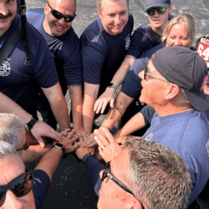 Group of firefighters with hands together in a team huddle.