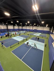 Image of professional-grade pickleball courts with acrylic-coated surfaces, clean, brightly marked lines, court dividers, permanent nets and great lighting, ensuring optimal playing environment for both casual and competitive players.