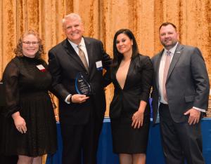 Director Rachel Rossi and CLS CEO Jeff Harvey stand next to award winner.