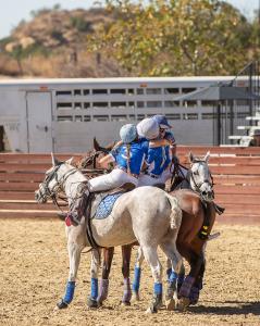 three arena polo players hug in celebration