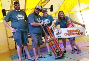 Gettin' Basted BBQ Competition Team Accepting a Grand Champion trophy and banner at a barbecue competition