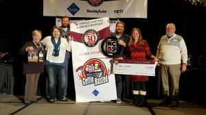 Brad Leighninger and family accepting KCBS award with a banner, check, and KCBS sign on stage at a banquet