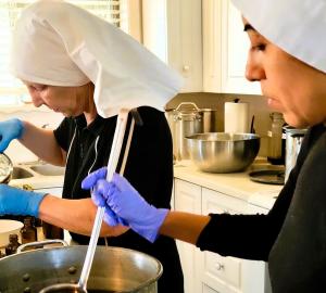 two sisters standing at a counter both busy with pouring or stirring