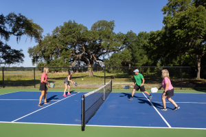 four adults playing pickleball at Lakeshore by Simple Life