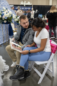 Engaged couple at the wedding show looking at photographers photo album.