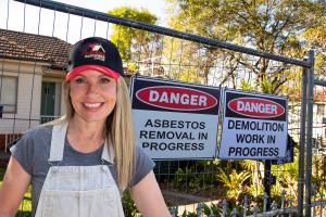 Image of Cherie Barber, Australia's Renovation Queen in front of a 1960s home which is made of asbestos cement with cladding over the top of the fibro. There is fencing around the property with asbestos removal signage.