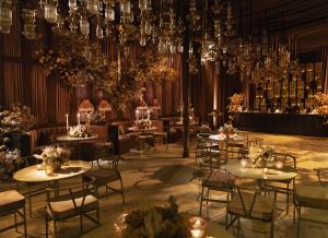 Luxurious event space designed by Revelry Event Designers featuring amber-toned draping, cascading floral installations, vintage table lamps, and candlelit tables adorned with lush floral centerpieces