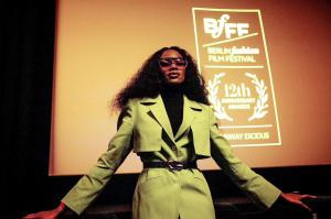 Woman wearing sunglasses standing in front of a cinema screen.