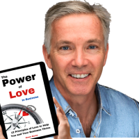 Owen Burns holding his book, The Power of Love in Business: 12 Principles to Help You and Your Business Thrive, emphasizing how love-driven leadership can transform teams and businesses.