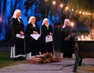 4 sisters standing in the winter night beside a fire burning for the winter solstice