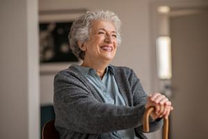 An older woman sitting comfortably on a leather chair with a warm cup of tea, looking thoughtful. The cozy setting and soft lighting symbolize peace of mind and security, aligning with the values of senior insurance solutions that prioritize comfort and c