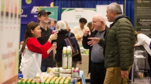 An image of two older men on the right speaking with a younger woman who is an exhibitor at the Wellness Show in Vancouver.