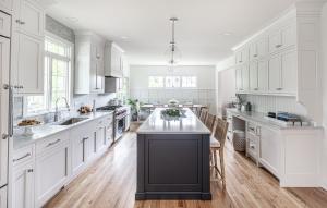 A luxury kitchen with white cabinets and an island with a black end cap.