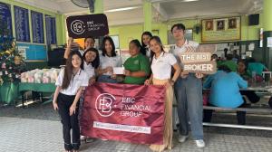 EBC Financial Group volunteers pose with a banner and supplies at a community centre, supporting visually impaired students through their CSR initiative - EBC