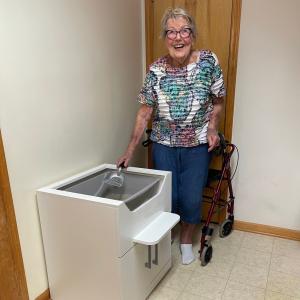 Elderly woman using a wheelchair easily cleans the LoftyLoo™ Raised Litter Box, designed for safety and accessibility. LoftyLoo is the best elevated cat litter box, dog-proof, and easy to clean.