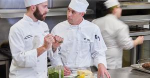 Chef instructing student preparing pesto