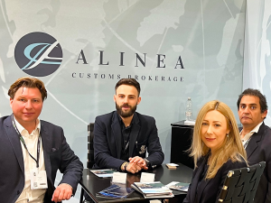 A photo of 4 people with a glass background showing the company name Alinea Customs