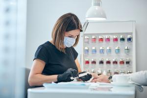 a close-up of a serious woman focused on doing a manicure.