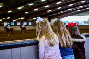 three young girls watching an arena polo competition