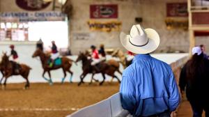 a man in a cowboy hat watches as arena players compete in Texas Arena League at San Antonio Rose Palace