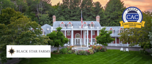 A scenic view of Black Star Farms' main building, surrounded by lush greenery, with the IBCCES Certified Autism Center™ badge prominently displayed.