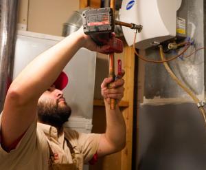 J. Blanton Plumbing technician repairing a water heater, showcasing the company’s expertise in plumbing maintenance, plumbing repair, and water heater fixes for Chicagoland businesses facing winter challenges.