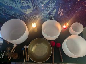 quartz crystal singing bowls and himalyan singing bowl with various mallots arranged on a table with candles