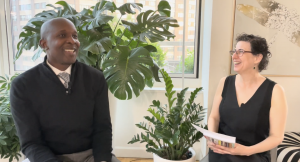 Drs. Damon Tweedy and Danielle Ofri seated together and smiling in light room among plants
