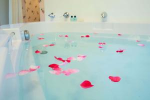 A large soaking tub with rose petals floating inside a cute cottage