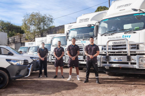 4 Two Men and a Truck team members standing in front of 6 trucks and 2 utes ready for work