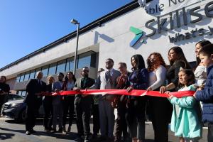 SkillsetGroup executives, employees, and local officials hold up the ceremonial ribbon and scissors for the ribbon cutting ceremony.