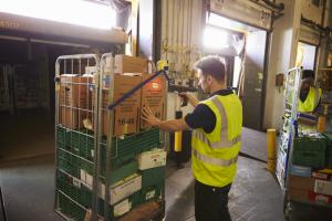 Man in a warehouse holds and scans a box for delivery