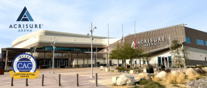 Exterior view of Acrisure Arena under a clear sky with signage and certification plaque visible.