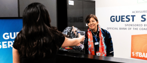 Person handing over a clear plastic bag with items to another individual at a guest services desk.