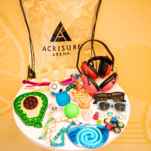 Assorted small toys and items on a plate with a clear plastic bag marked "Acrisure Arena" in the background.