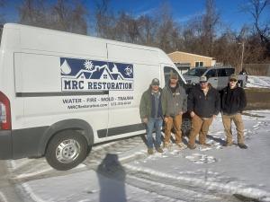 MRC Restoration team standing in front of their branded company van in the snow after completing a construction project at the Desloge City Pound.