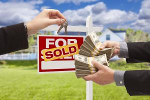 A real estate transaction showing a 'For Sale' sign with a 'Sold' sticker, a hand giving house keys, and another hand holding stacks of cash.